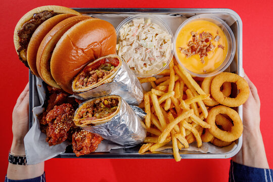 A young woman is holding a tray of American street food.