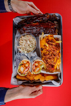 A young woman is holding a tray of American street food.
