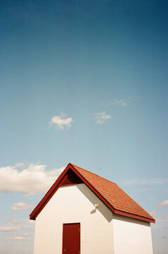 Small white building with red roof under sunny sky