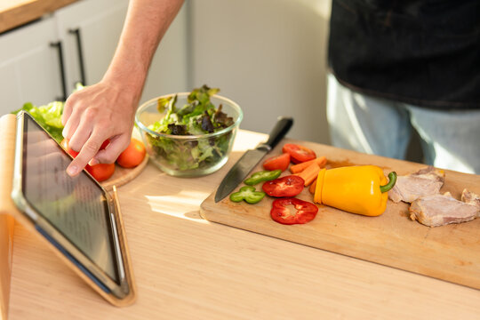 Close up of hands touching tablet's screen follow online recipe while cooking. 