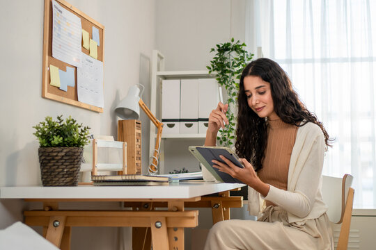 Hispanic businesswoman using digital tablet while working from home. 