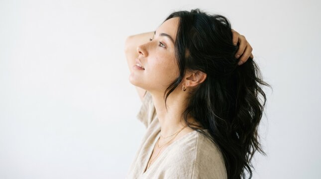 Young Woman with Long Dark Hair Touching Her Head in Natural Light.