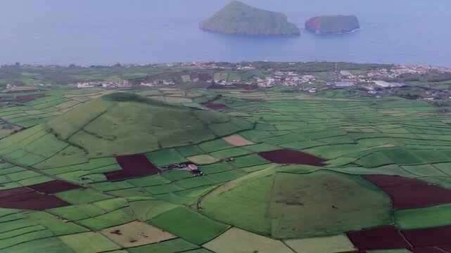 Aerial view of the lush green volcanic landscape and patchwork fields of Terceira Island, Azores, Portugal.