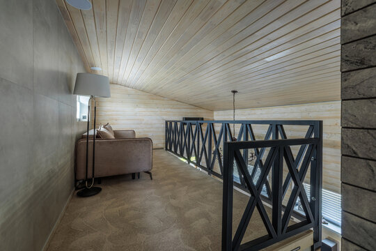Mezzanine Floor Interior with Sofa, Metal Railing, and Sloped Ceiling