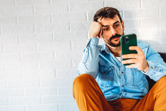 Tired, frustrated man staring at his phone, digital overload, mental fatigue, technology frustration