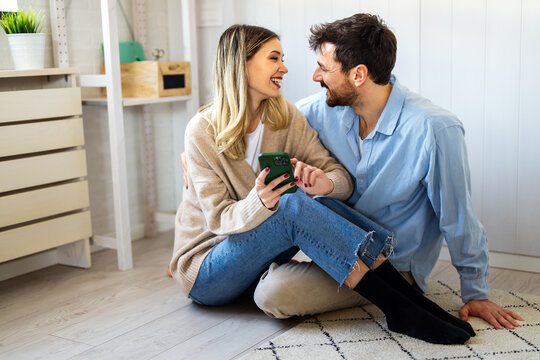Smiling young couple embracing while looking at smartphone. Multiethnic couple sharing social media
