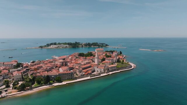 Aerial view of the historic old town of Porec with its red-tiled rooftops and the Euphrasian Basilica surrounded by the Adriatic Sea in Porec, Istria County, Croatia.