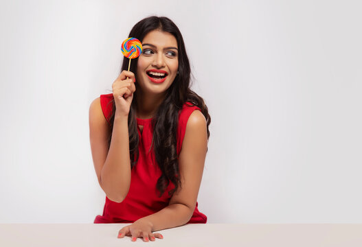 Portrait of a young woman holding a lollipop in hand.