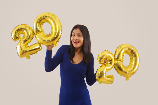 Young woman holding 2020 golden balloons during a new year party. 