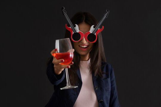 Young woman wearing funky glasses and holding a wine glass at new year eve party. 