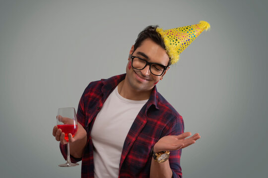 Young man wearing a party hat and holding a wine glass at new year eve party. 