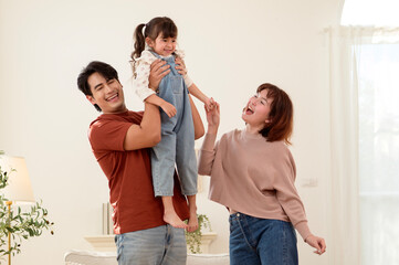 Fototapeta premium Family Enjoys Time Together Indoors While Playing With Their Young Daughter in a Bright Living Room