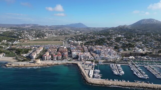 Aerial view of Moraira town and marina with boats, historic castle, and coastal landscape in Moraira, Valencian Community, Spain.