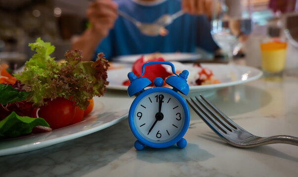 The intermittent fasting breakfast concept, healthy food with alarm clock indicating meal time background