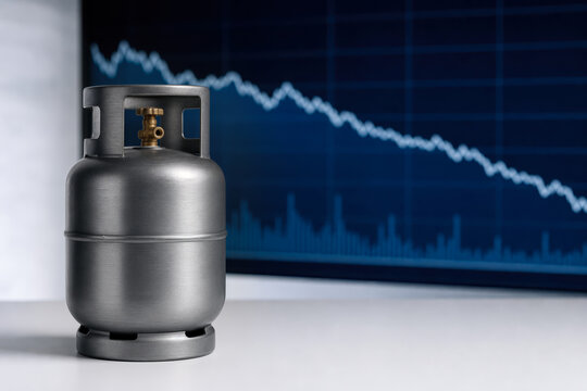 Unbranded metallic LPG cylinder on white surface with downward trending financial chart on digital screen symbolizing gas price correction energy market analysis and subsidy impact report