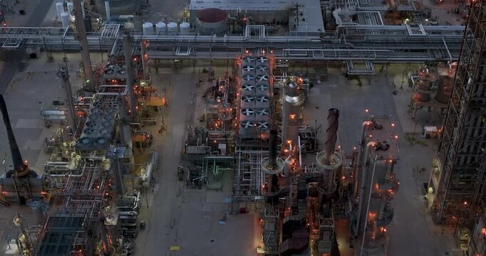 Aerial view of the Joliet oil refinery featuring complex industrial piping, cooling fans, and illuminated structures at dusk in Joliet, Illinois, United States.