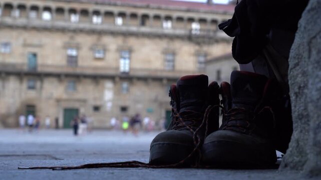 Detalle de unas botas viejas de peregrino en la plaza del Obradoiro, mientras su due&ntilde;o descansa tras completar el Camino de Santiago.