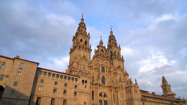 Catedral de Santiago de Compostela iluminada por la luz naranja del atardecer, destacando su fachada y torres sobre la plaza del Obradoiro.