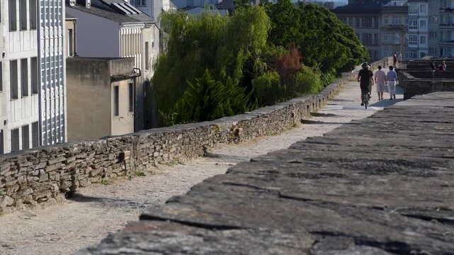 Vecinos paseando por la parte superior de la muralla romana de Lugo, disfrutando de este hist&oacute;rico paseo elevado que rodea el casco antiguo de la ciudad.