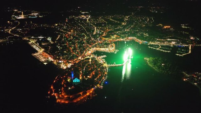 Aerial view of the historic old town of Rovinj illuminated at night, featuring the Church of St. Euphemia and coastal streets in Rovinj, Istria County, Croatia.