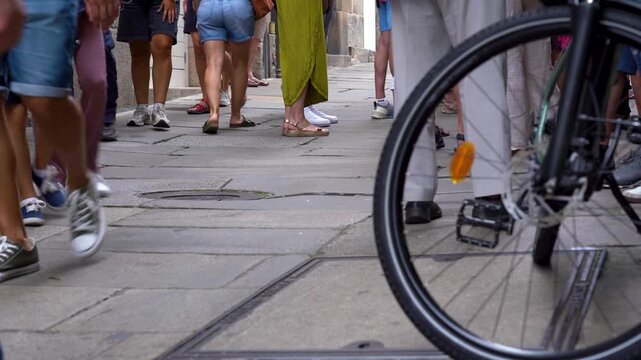 Detalle de las piernas de varios turistas caminando por las calles de piedra del casco antiguo de Santiago de Compostela.