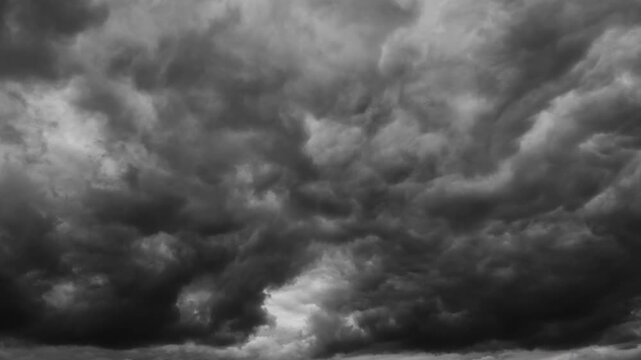 Dark moody storm clouds moving across the sky in a dramatic timelapse background. Heavy gray cumulus clouds creating an intense atmospheric weather background for cinematic use