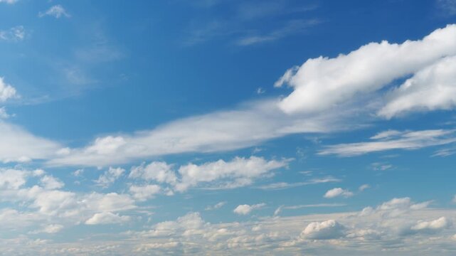 Beautiful blue sky background with moving white clouds in a bright sunny day timelapse. Fluffy cumulus clouds drifting across the clear atmosphere for a peaceful nature background