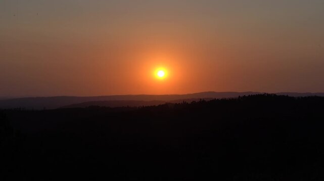 Timelapse de un atardecer con cielo despejado, mientras el sol desciende lentamente hasta desaparecer entre las monta&ntilde;as del horizonte.