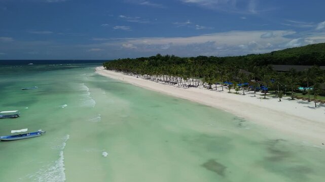 Aerial view of Dumaluan Beach with white sand, turquoise water, and palm trees along the coastline in Panglao, Central Visayas, Philippines.