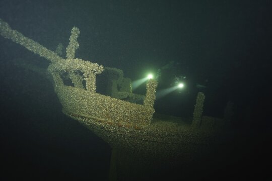 Divers with torches examine an old shipwreck overgrown with mussels, quagga triangle mussel (Dreissena rostriformis bugensis), invasive species, in the dark, dive site wreck of the Jura, Lake Constance, Bottighofen, Switzerland, M&uuml;nsterlingen, Germany