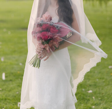 Bride Holding Bouquet Under Soft Flying Veil