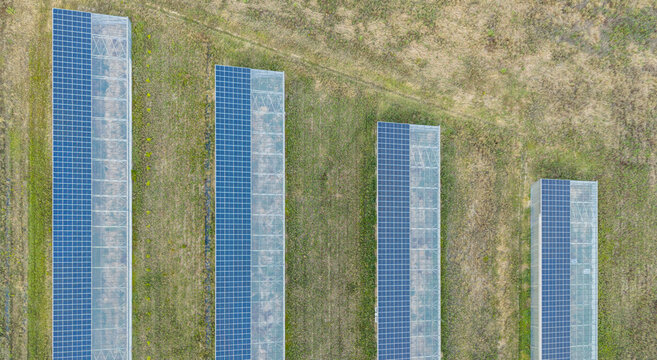Aerial view of modern agricultural greenhouses with rooftop solar panels, illustrating agrivoltaic infrastructure and sustainable farming in Loriol-sur-Drome, Auvergne-Rhone-Alpes, France.