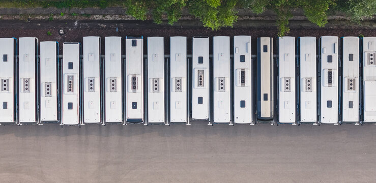 Aerial view of a fleet of modern public transport buses parked in parallel at a depot, showcasing geometric urban mobility in Loriol-sur-Drome, Auvergne-Rhone-Alpes, France.