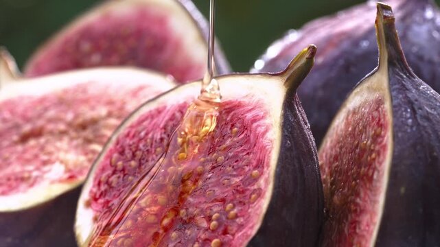 Sweet golden honey pouring onto a fresh ripe sliced fig fruit close up macro shot healthy organic dessert food background