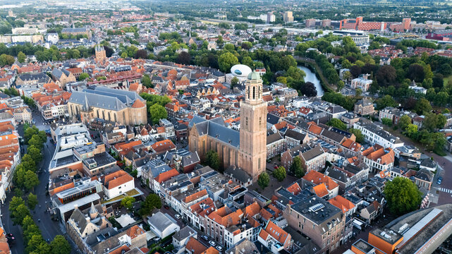 Aerial view of the historic Grote of Sint-Michaelkerk surrounded by dense urban rooftops, narrow streets, and lush green trees in the city center of Zwolle, Overijssel, Netherlands.