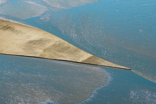 Aerial view of a sandbar emerging from low water in the river, showcasing the natural patterns and textures of the riverbed in Poland.