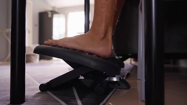 Bare Foot Presses Adjustable Footrest Beneath a Desk, Supporting Comfortable Seated Posture and Workplace Wellbeing