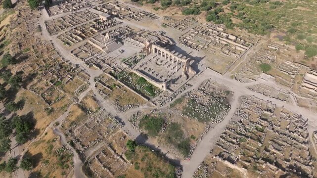 High-angle drone view of the civic center at the UNESCO World Heritage-listed Volubilis Archaeological Site in Morocco, revealing the Capitol, Basilica, and surrounding Roman urban layout.