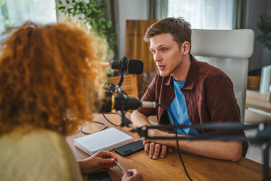 Young man recording podcast interview with microphones