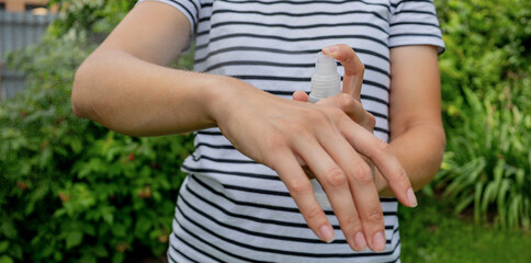 Obraz premium Woman applying insect and mosquito spray on arm for outdoor protection.