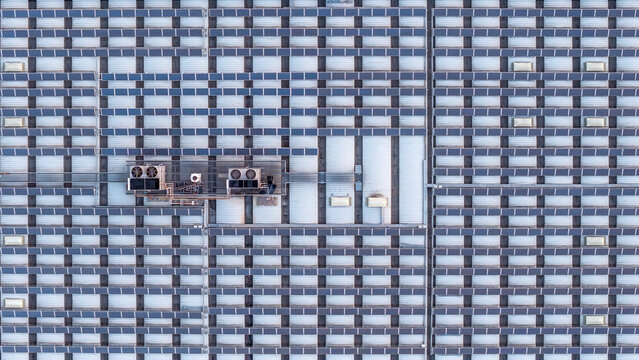 Aerial view of a datacenter roof covered in rows of solar panels with integrated HVAC cooling units in Settecamini, Lazio, Italy.