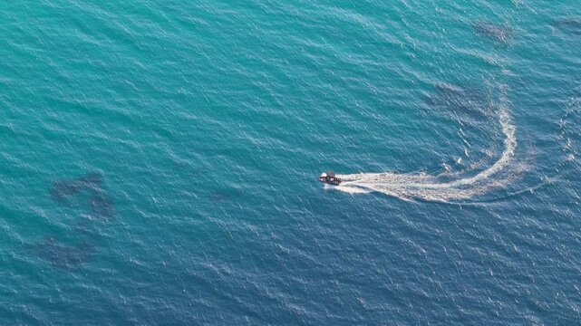 Small Motorboat Carving a Wake Across Turquoise Greek Sea