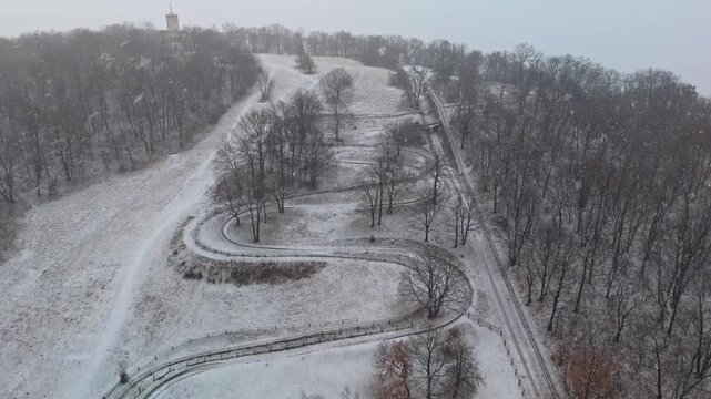 Visegr&aacute;d, Hungary bobsleigh track winding through snowy forest in the Visegr&aacute;d Mountains during snowfall, with closed curves and winter landscape seen from an aerial view.