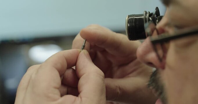 Technician inspecting a tiny precision component with a jeweler loupe, demonstrating detailed quality inspection, engineering, and precision manufacturing.