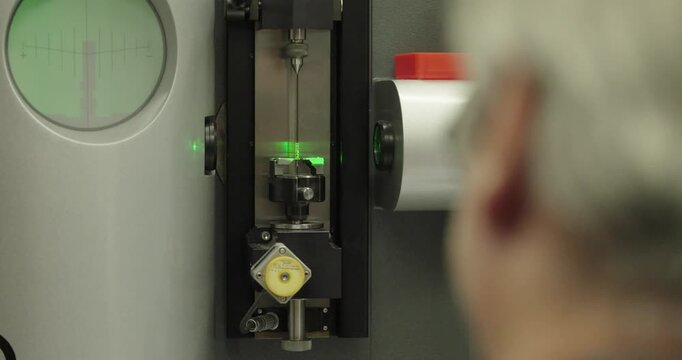 Industrial precision measuring machine inspecting a small metal component with laser guidance, demonstrating quality control, metrology, and high-accuracy manufacturing.