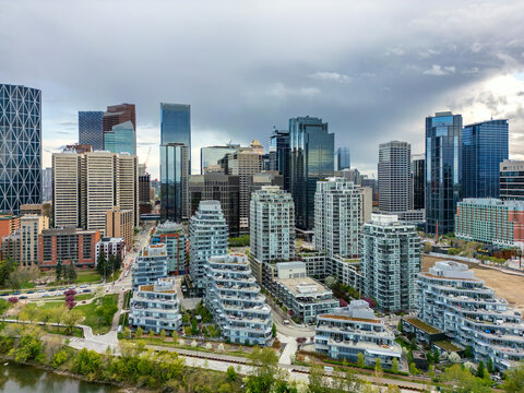 Aerial view of the Calgary skyline featuring modern skyscrapers, residential buildings, and the Bow River under a cloudy sky in Calgary, Alberta, Canada.