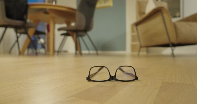 Eyeglasses falling onto the floor in slow motion, illustrating accidental drops, fragile objects, and the risk of damage to eyewear.