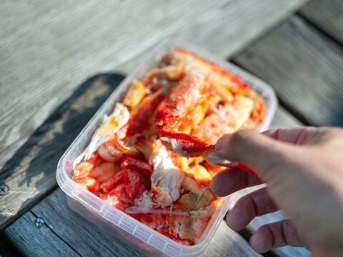  hand picking a shrimp from a plastic box