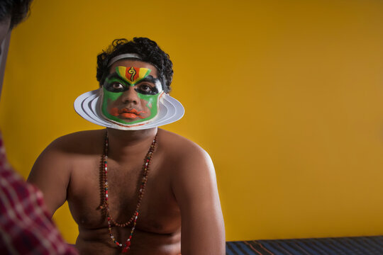 Kathakali dancer sitting and getting his final stages of makeup.done.