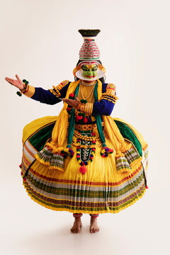 Kathakali dancer dancing in front of a white background.